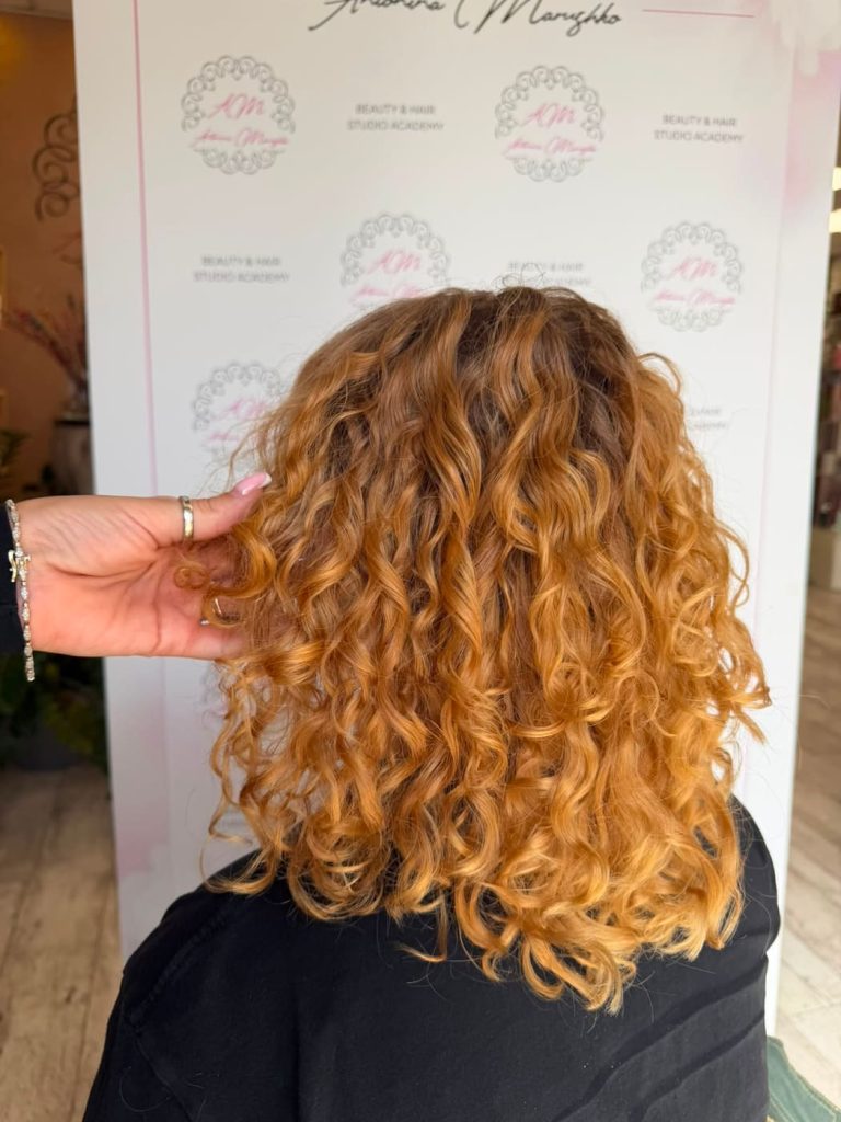 Miedziany blond po trwałej bio — sprężyste loki średniej długości