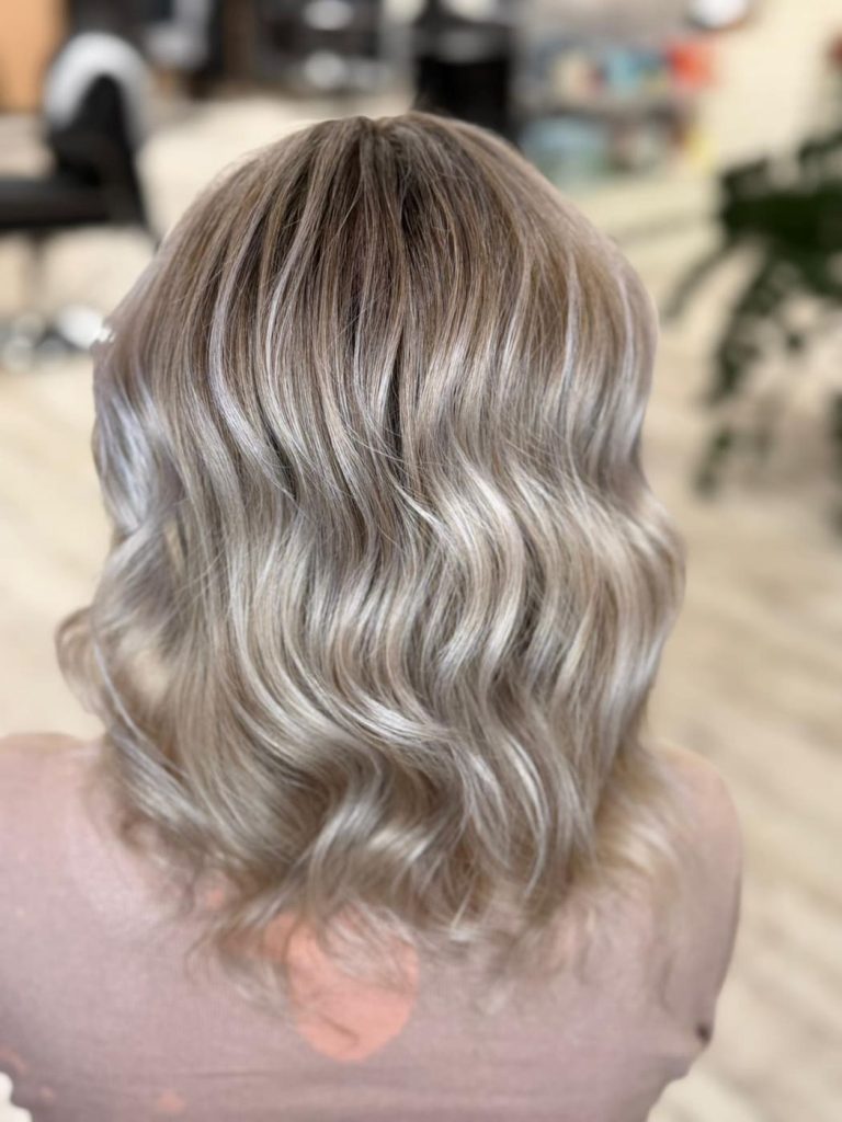 Beżowy blond z chłodnymi refleksami na falowanych włosach do ramion